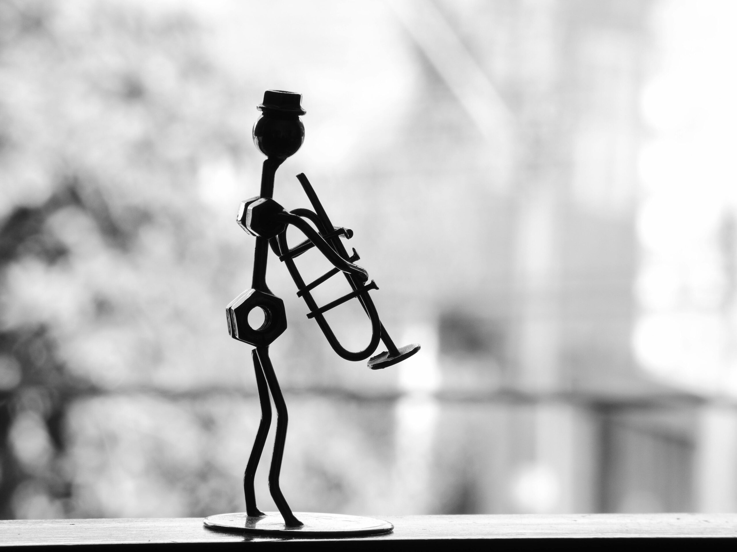 Black and white image of a metal sculpture of a trumpet player, showcasing artistic craftsmanship.