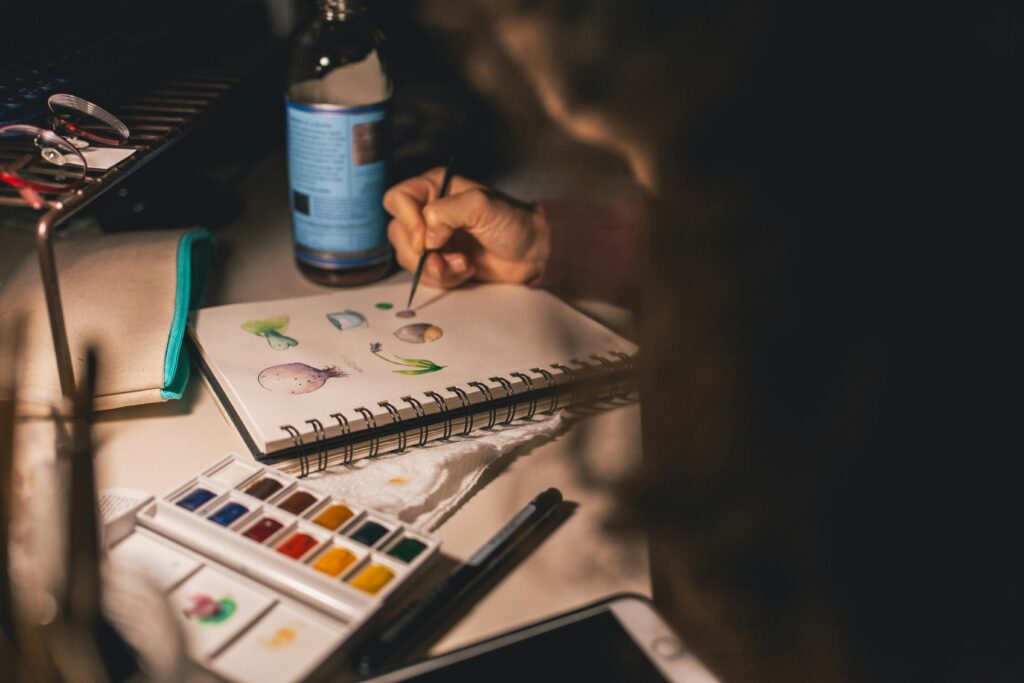 Artist painting with watercolors in a notepad at a desk. Creative process indoors. art design drawing