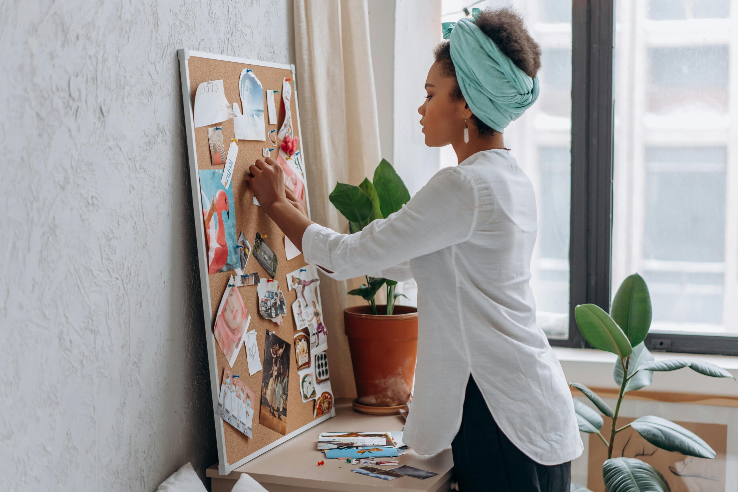 Woman in white shirt arranging a vision board in a modern apartment. art-design-template-