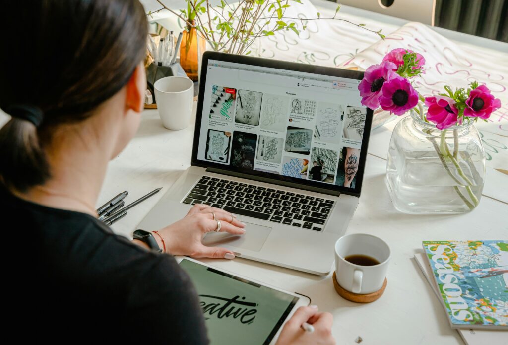 Woman in a creative workspace using a laptop and tablet for calligraphy. Artistic and tech-driven environment. dream-inspired art blog