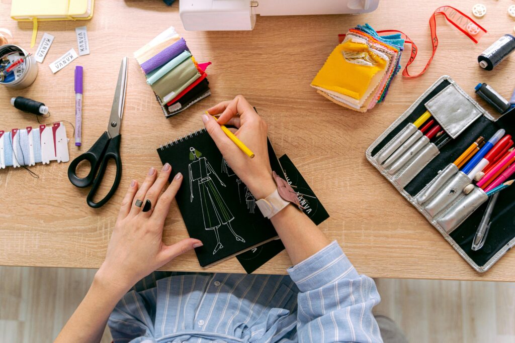Designer sketching fashion outfits in a vibrant workshop with colorful fabrics and tools. creative art pencil drawing ideas